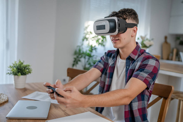 хлопчик білий підліток молодий студент насолоджується гарнітурою VR віртуальної реальності вдома під час гальмування - Фото, зображення