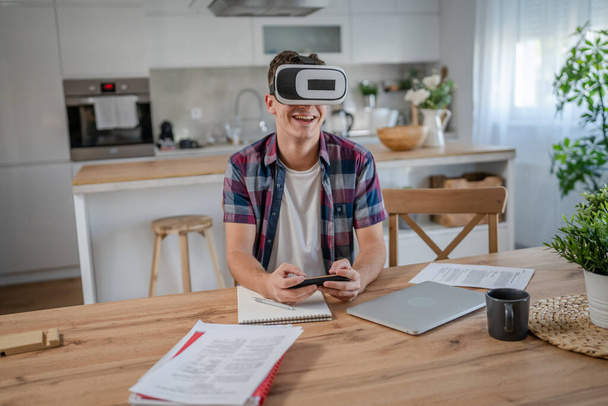 menino caucasiano adolescente jovem estudante desfrutar virtual realidade VR fone de ouvido em casa enquanto tomar um freio - Foto, Imagem