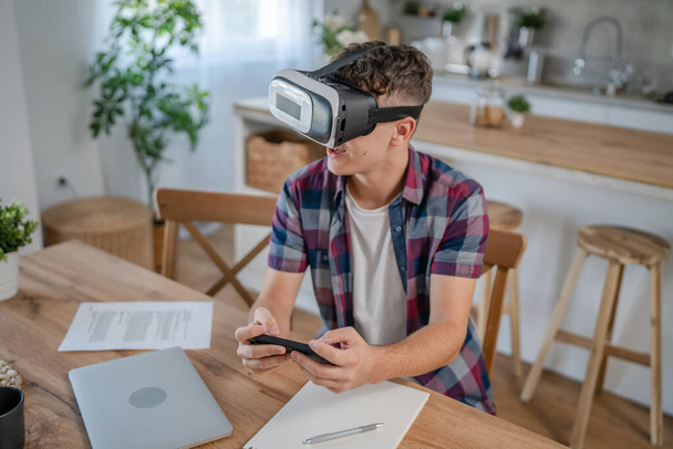 fiú kaukázusi tinédzser fiatal férfi diák élvezze virtuális valóság VR headset otthon, miközben a fék - Fotó, kép