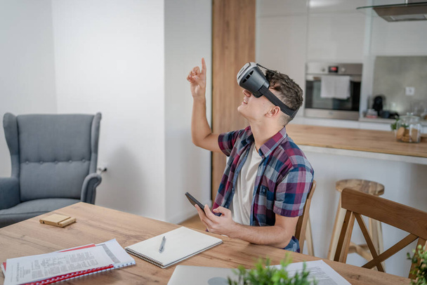 chico caucásico adolescente joven estudiante disfrutar de realidad virtual VR auriculares en casa mientras tomar un freno - Foto, Imagen