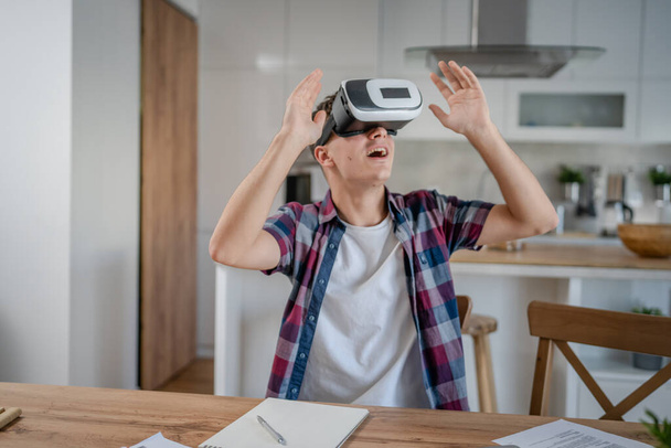 chico caucásico adolescente joven estudiante disfrutar de realidad virtual VR auriculares en casa mientras tomar un freno - Foto, imagen
