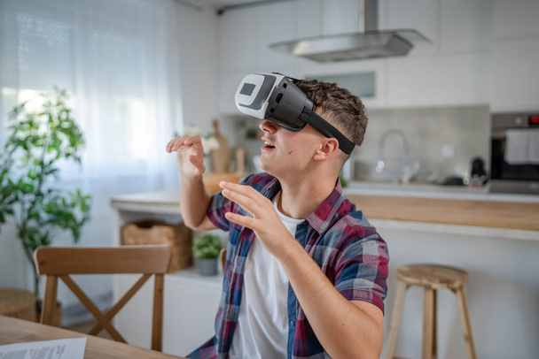 chłopiec biały nastolatek młody mężczyzna student ciesz się wirtualna rzeczywistość VR zestaw słuchawkowy w domu podczas wziąć hamulec - Zdjęcie, obraz