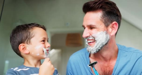 Αστείο, ξύρισμα και ένας πατέρας να διδάσκει στο γιο του για περιποίηση ή υγιεινή στο μπάνιο του σπιτιού τους μαζί. Πρόσωπο, οικογένεια και παιδιά με ένα αγόρι που μαθαίνει να ξυρίζεται με τους μόνους γονείς του.. - Πλάνα, βίντεο
