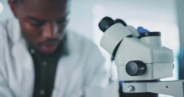 Zwarte man, wetenschapper en microscoop, analyse in laboratorium met medisch onderzoek en controlemonster in experiment. Toekomst, dokter en onderzoek met wetenschappelijke studie en leren met pathologie. - Video