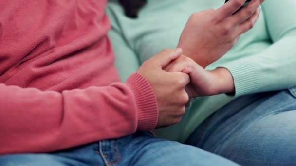 Κρατώντας τα χέρια, αγκαλιά και ζευγάρι στον καναπέ με τηλέφωνο για τα μέσα κοινωνικής δικτύωσης, streaming ή συνδρομή βίντεο στο σπίτι. Αγάπη, αγκαλιά και γυναίκα με άντρα και smartphone σε ένα σαλόνι για online επικοινωνία. - Πλάνα, βίντεο