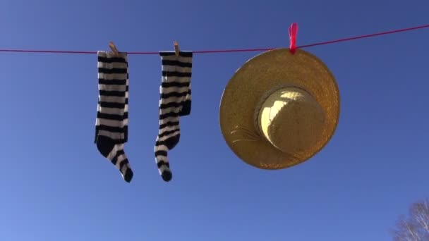 Línea de lavandería con calcetines de mujer y sombrero de paja de verano en el viento en el fondo del cielo
 - Imágenes, Vídeo