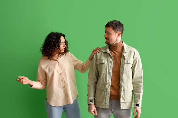 Upset young couple on green background - Foto, afbeelding