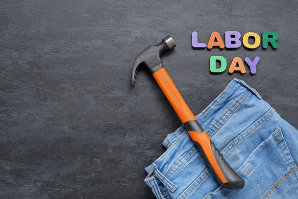 Jeans, hammer and text LABOR DAY on black grunge background - Photo, Image