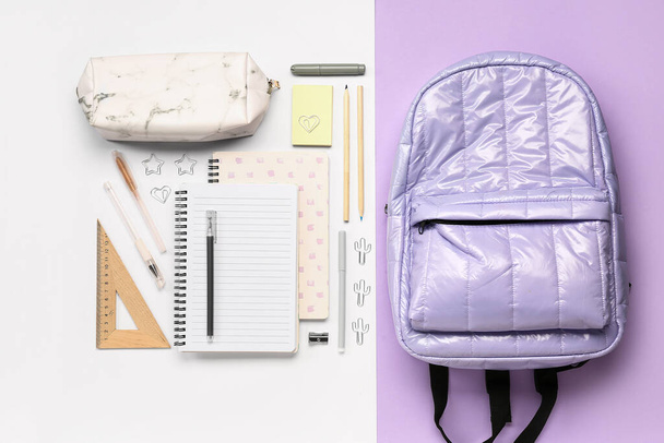 Стильный школьный рюкзак с карандашом и различными канцелярскими принадлежностями на цветном фоне - Фото, изображение
