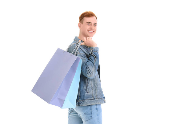 白い背景に隔離されたショッピングバッグを持つ幸せな若い赤毛の男. ブラックフライデーセール - 写真・画像