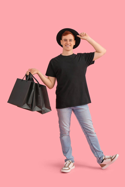 Feliz jovem ruivo com sacos de compras no fundo rosa. Black Friday venda - Foto, Imagem