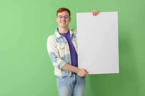 Счастливый молодой рыжий мужчина с чистым плакатом на зеленом фоне. Чёрная пятница - Фото, изображение