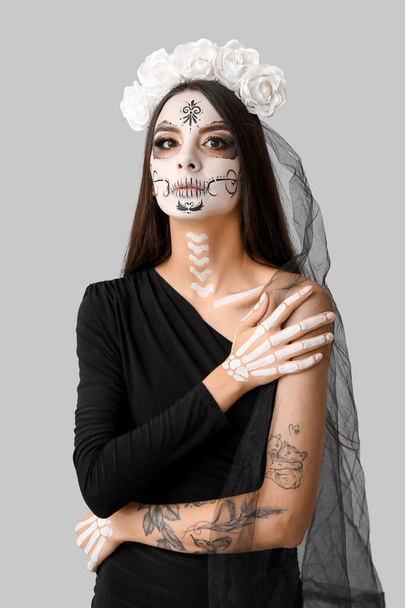Красива молода жінка, одягнена як мертва наречена на вечірку на Хелловін на сірому фоні - Фото, зображення