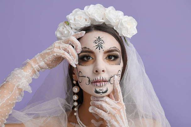 Mooie jonge vrouw verkleed als dode bruid voor Halloween feest op paarse achtergrond - Foto, afbeelding