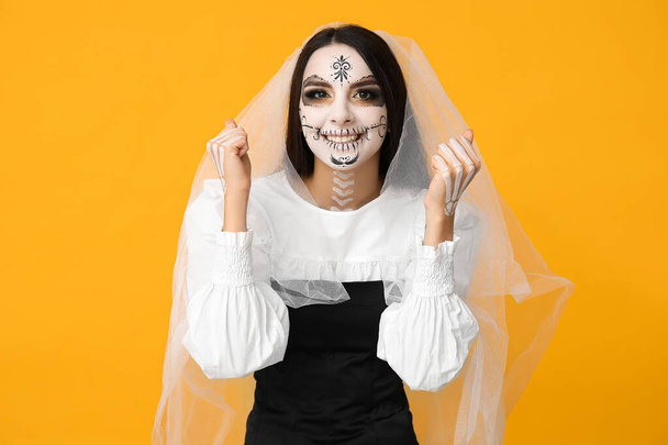 Belle jeune femme habillée en mariée morte pour la fête d'Halloween sur fond jaune - Photo, image
