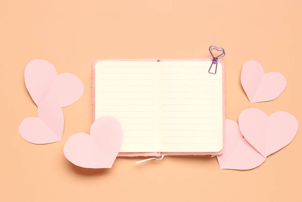 Beautiful paper hearts with open notebook on orange background. National Sweetest Day - Photo, Image
