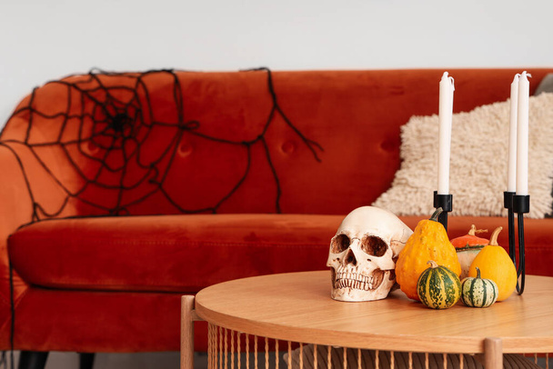 Halloween sütőtök koponya és gyertyák az asztalon a nappaliban, közelkép - Fotó, kép