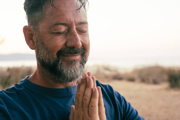  дорослий чоловік молиться і медитує на відкритому повітрі в жесті релаксації - Фото, зображення