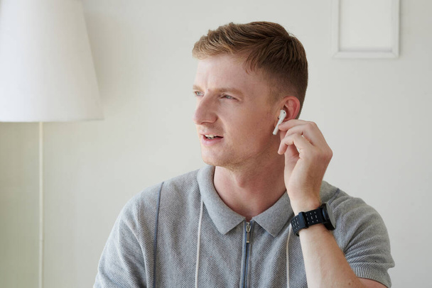 Νεαρός που φοράει ακουστικά όταν καλεί συνάδελφο - Φωτογραφία, εικόνα