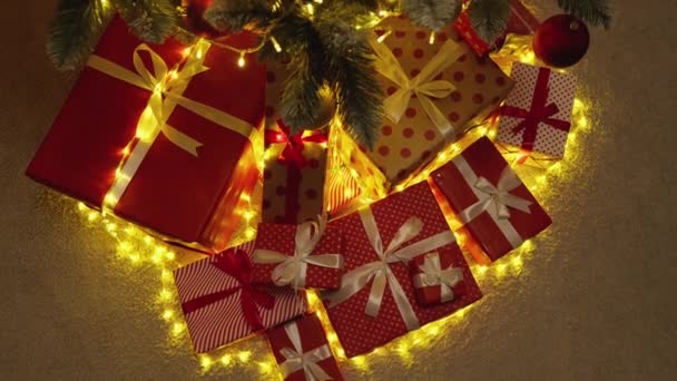 Λεπτομέρειες για τη χριστουγεννιάτικη διάθεση: το χριστουγεννιάτικο δέντρο, τα δώρα και τα ελαφριά φώτα σας βυθίζουν σε μια εορταστική αίσθηση. Αστείες εορταστικές εκδηλώσεις φωτός: ένα χριστουγεννιάτικο δέντρο που λάμπει στο σκοτάδι δίνει μια αίσθηση γιορτής - Πλάνα, βίντεο