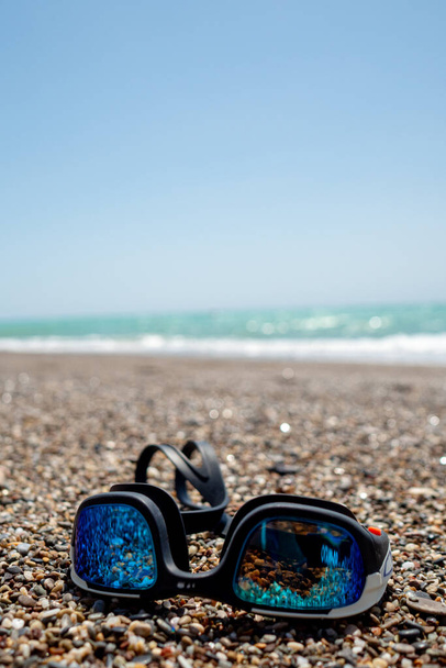 Zwembrillen op een deken tijdens warme zomerdag met wazige achtergrond, vakantie en reisconcept - Foto, afbeelding