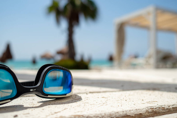 okulary kąpielowe układające się na kocu w gorący letni dzień z zamazanym tłem, wakacyjnym i podróżniczym konceptem - Zdjęcie, obraz