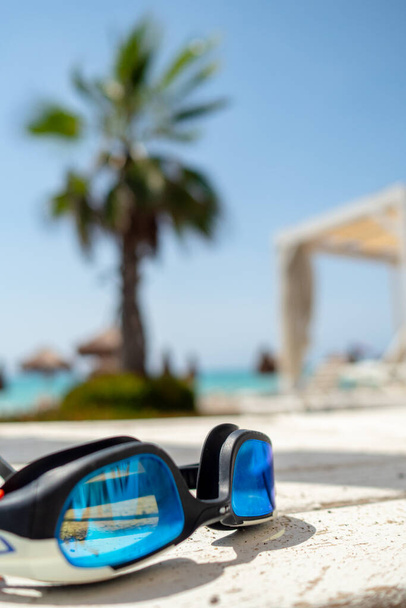 gafas de baño colocadas sobre una manta durante el caluroso día de verano con fondo borroso, vacaciones y concepto de viaje - Foto, Imagen