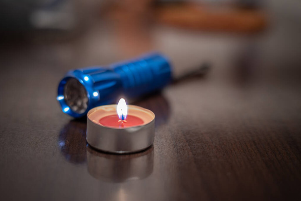 Burning candle and flashlight. Blackout due to the war in Ukraine - Photo, Image