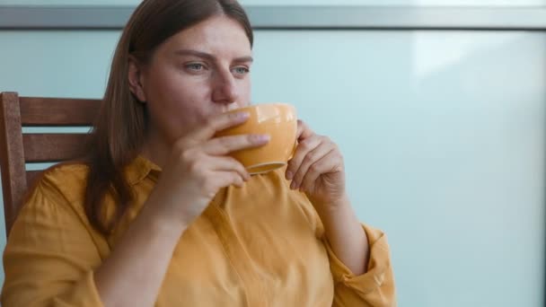 Atractiva mujer de ensueño pacífica sosteniendo taza disfrutar de la bebida de té mañana vigorizante bebida de café mientras se sienta en su terraza.  - Metraje, vídeo