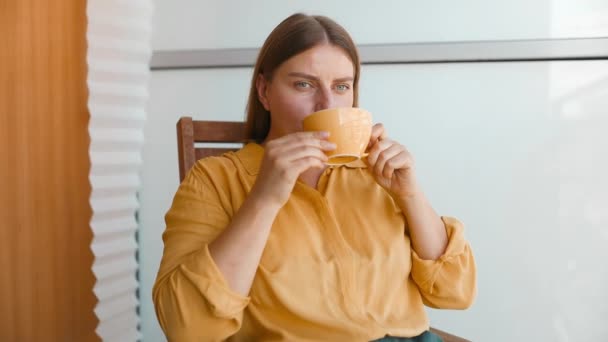 Atractiva mujer de ensueño pacífica sosteniendo taza disfrutar de la bebida de té mañana vigorizante bebida de café mientras se sienta en su terraza.  - Imágenes, Vídeo