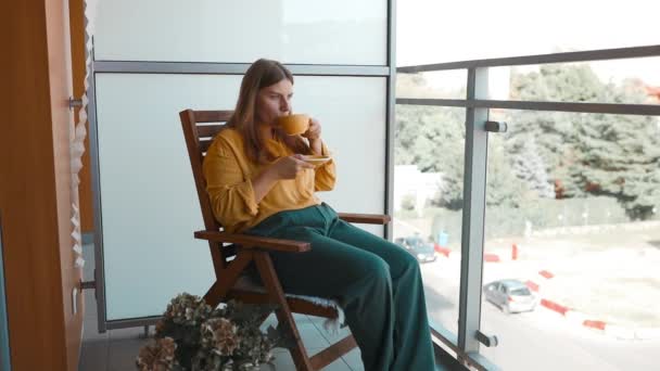Primer plano de atractiva mujer de ensueño pacífica sosteniendo taza disfrutar de la bebida de té mañana vigorizante bebida de café mientras se sienta en su terraza.  - Metraje, vídeo