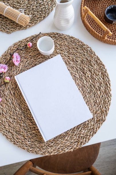 Book mockup design. Blank white book on dining table in asian style with tableware and napkins - Photo, Image