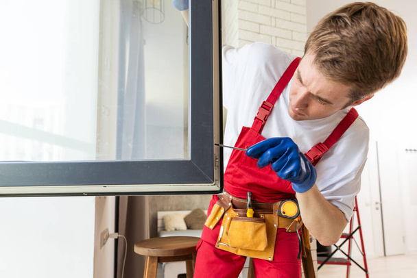 Een reparateur repareert ramen in nieuw appartement - Foto, afbeelding