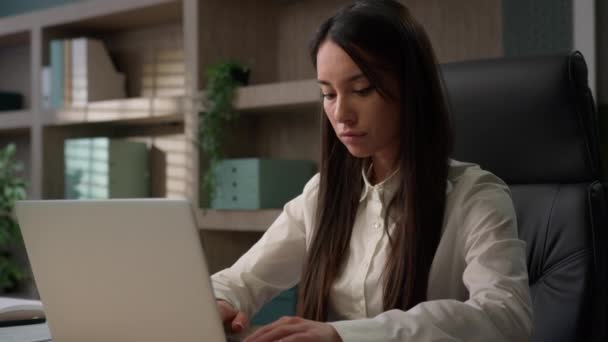 Кавказская вдумчивая деловая женщина серьезная задумчивая деловая женщина с ноутбуком в офисе работает в Интернете за столом работы думаю, что проект стартап решение мышления обдумать корпоративную проблему с компьютером - Кадры, видео