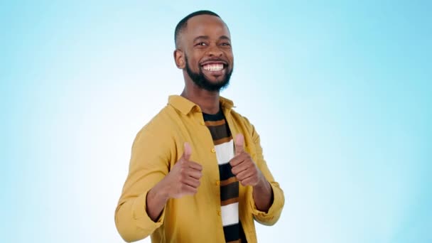 Thumbs up, face and man wink in studio for success, winning deal and achievement on blue background. Portrait, happy african model and blink eyes with like emoji, sign and voting in support of trust. - Footage, Video