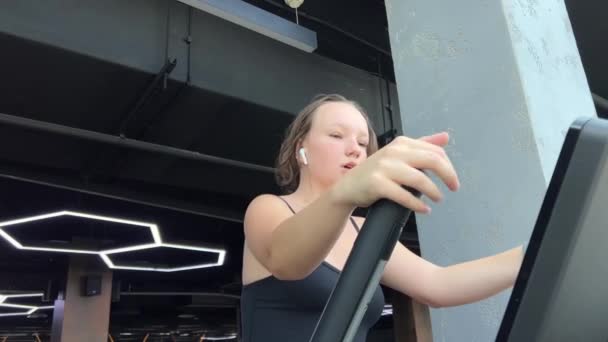 vytvořit krásnou postavu z mladého věku mladá žena dospívající dívka pracující v tělocvičně pumpování nohy na cvičebním stroji chůze po schodech oblek sluchátka Evropská Ukrajina Vinnitsa 09.09.2023 - Záběry, video