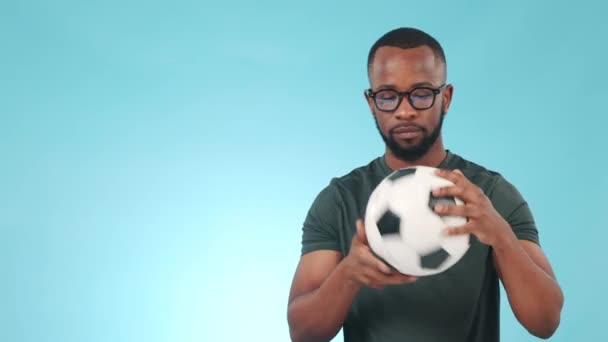 Thumbs up, soccer and black man catch ball happy for fitness or sports isolated in a studio blue background. Thank you, yes and young athlete or person in agreement of football success or goal. - Footage, Video