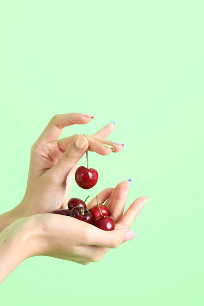 Azjatka trzyma owoc jagody w dłoni na żółtym tle. - Zdjęcie, obraz