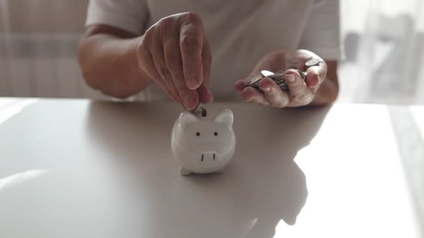 Senior 50s woman hand putting money coin into piggy for saving money wealth and financial concept. High quality FullHD footage - Footage, Video
