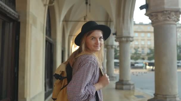 Привлекательная молодая туристка исследует новый город. Молодая стильная кавказская женщина-туристка гуляет по Рыночной площади во время восхода солнца в Кракове, Польша. Путешествует по Европе. Высокое качество FullHD - Кадры, видео