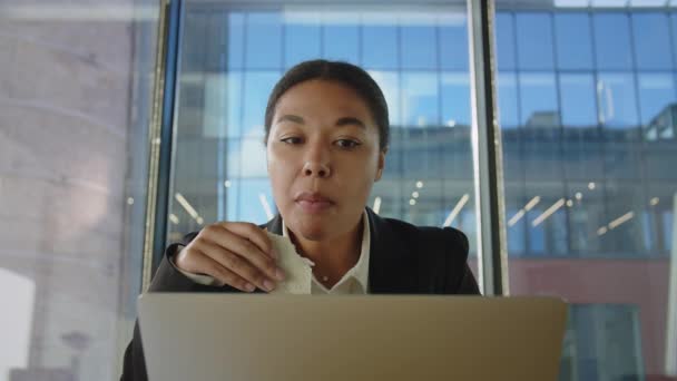 Młoda afro-amerykanka pisze na komputerze coś jedną ręką, a je drugą. Czarna kobieta w biurze je kanapki na śniadanie, bo nie ma czasu. stresująca praca i niezdrowe odżywianie - Materiał filmowy, wideo