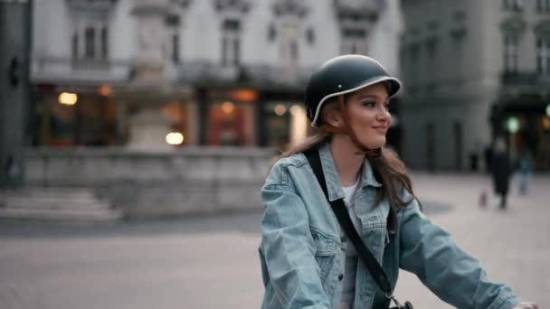 Mujer feliz con el pelo largo en casco de seguridad montar en bicicleta en la calle de la ciudad. Retrato exterior. Hermosa mujer disfrutando de estilo de vida activo. Concepto de relajación - Metraje, vídeo