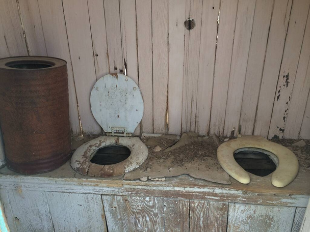Outhouse abbandonato con due vecchi sedili del water. Foto di alta qualità - Foto, immagini