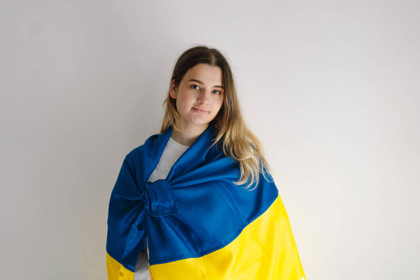 白い背景にウクライナの旗を持つ十代の少女の肖像画. ライフスタイル。 コピースペース - 写真・画像