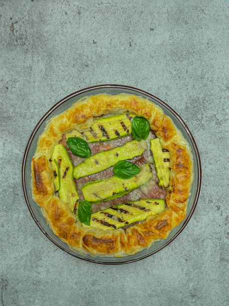 pastel salado con calabacines y albahaca en un plato redondo - Foto, imagen