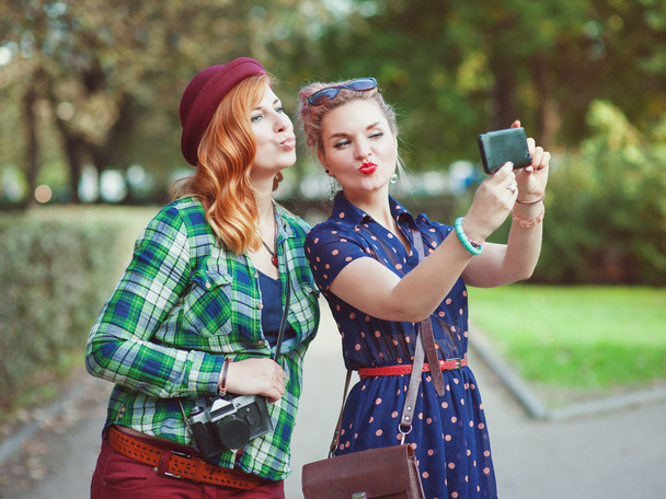 Deux belles filles hipster prenant des photos d'elles-mêmes sur la foule
 - Photo, image