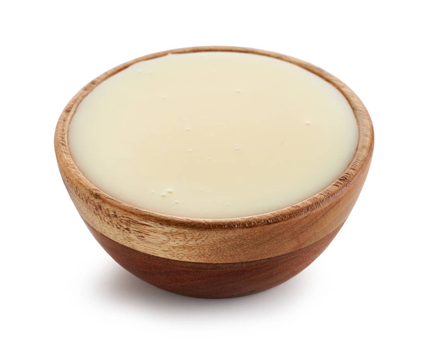συμπυκνωμένο γάλα σε ξύλινο μπολ απομονωμένο σε λευκό φόντο - Φωτογραφία, εικόνα