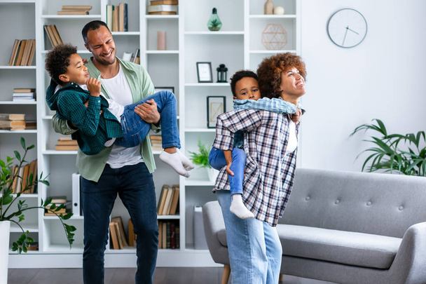 Happy parents with kids dancing in modern living room, having fun, playing active game, overjoyed mother and father with children siblings dancing to favorite music, jumping, celebrating event - Photo, Image