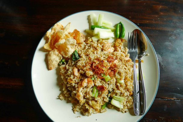 Shrimp Fried Rice, serviert mit etwas eingelegter Gurke und Melinjo-Crackern. - Foto, Bild