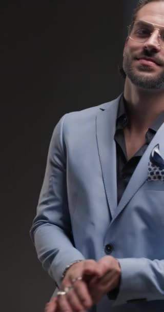knap gelukkig zakenman met bril kijken naar beneden kant, aanraken lippen en glimlachen in de voorkant van grijze achtergrond - Video